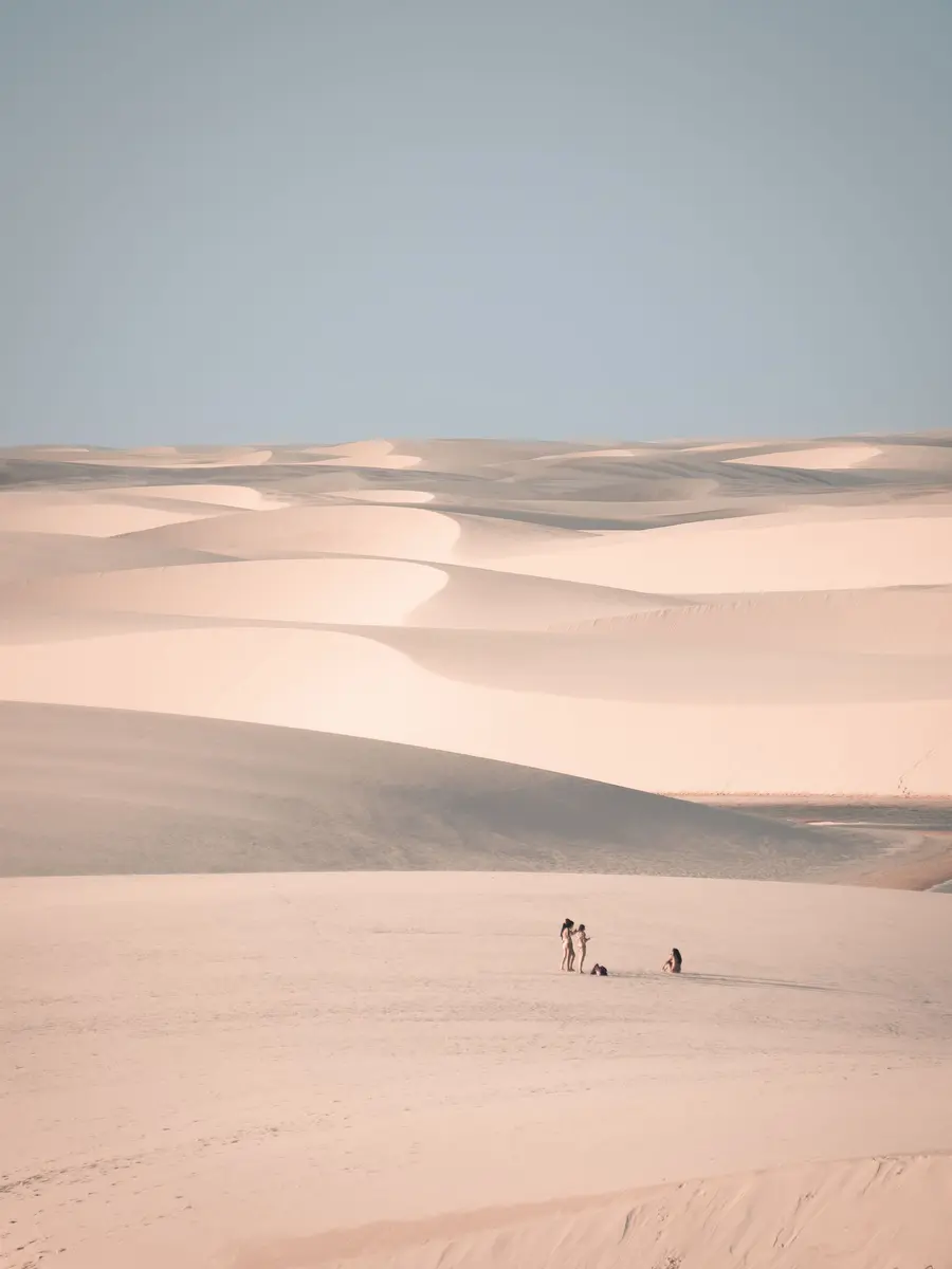 Dunas enormes com duas pessoas pequenas caminhando