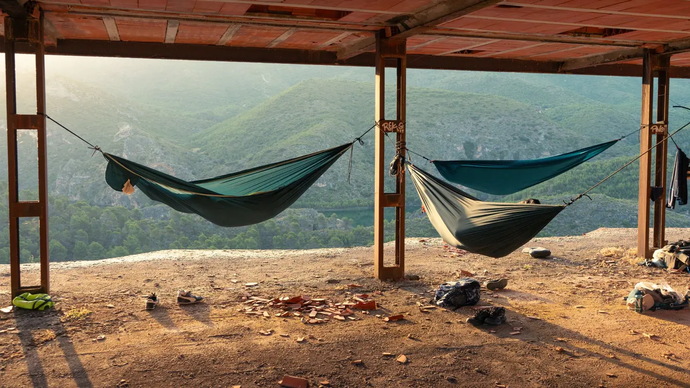 Duas redes armadas sob uma cobertura de madeira, com a paisagem ao fundo